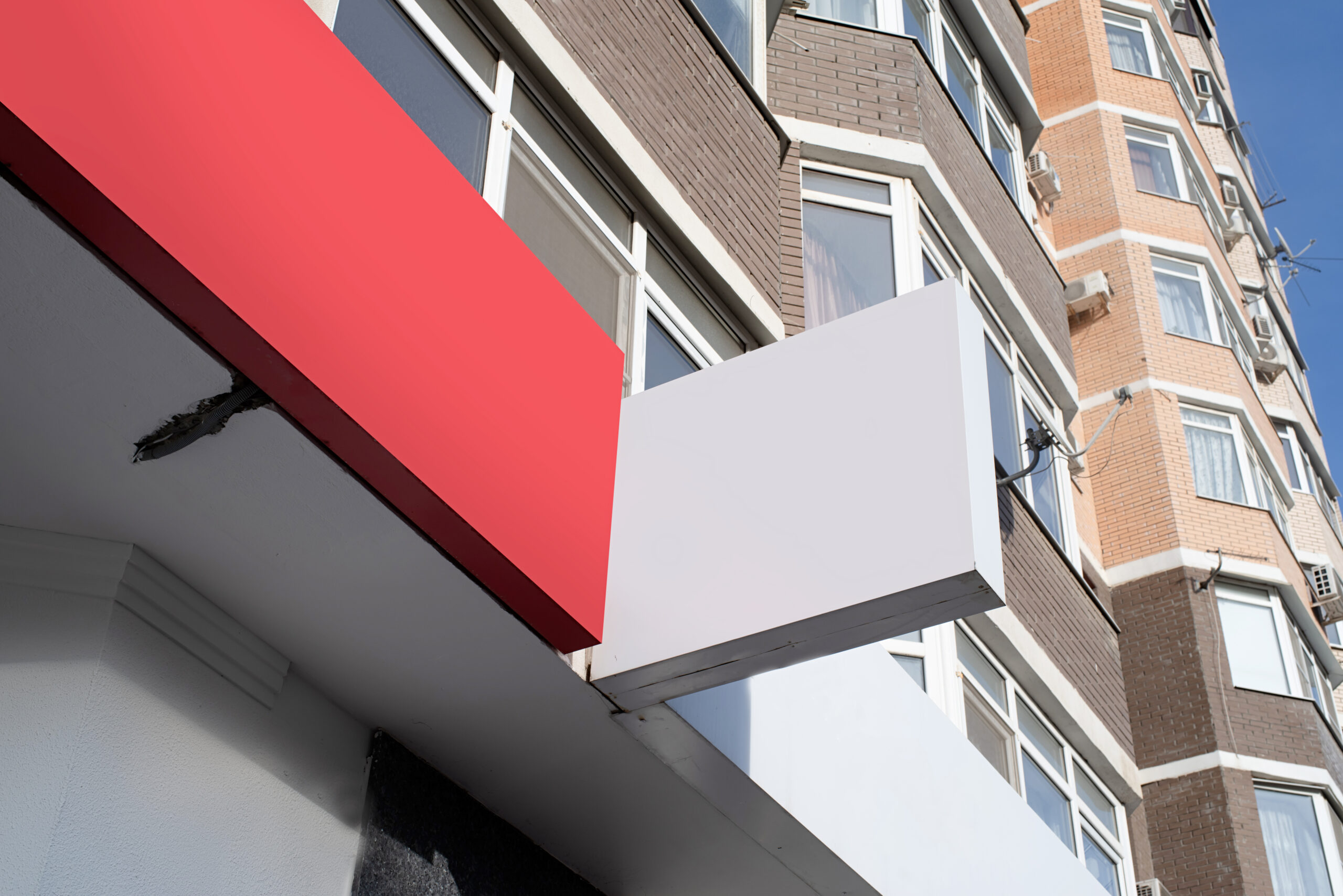 Blank projecting storefront sign mounted on the exterior of a commercial building.