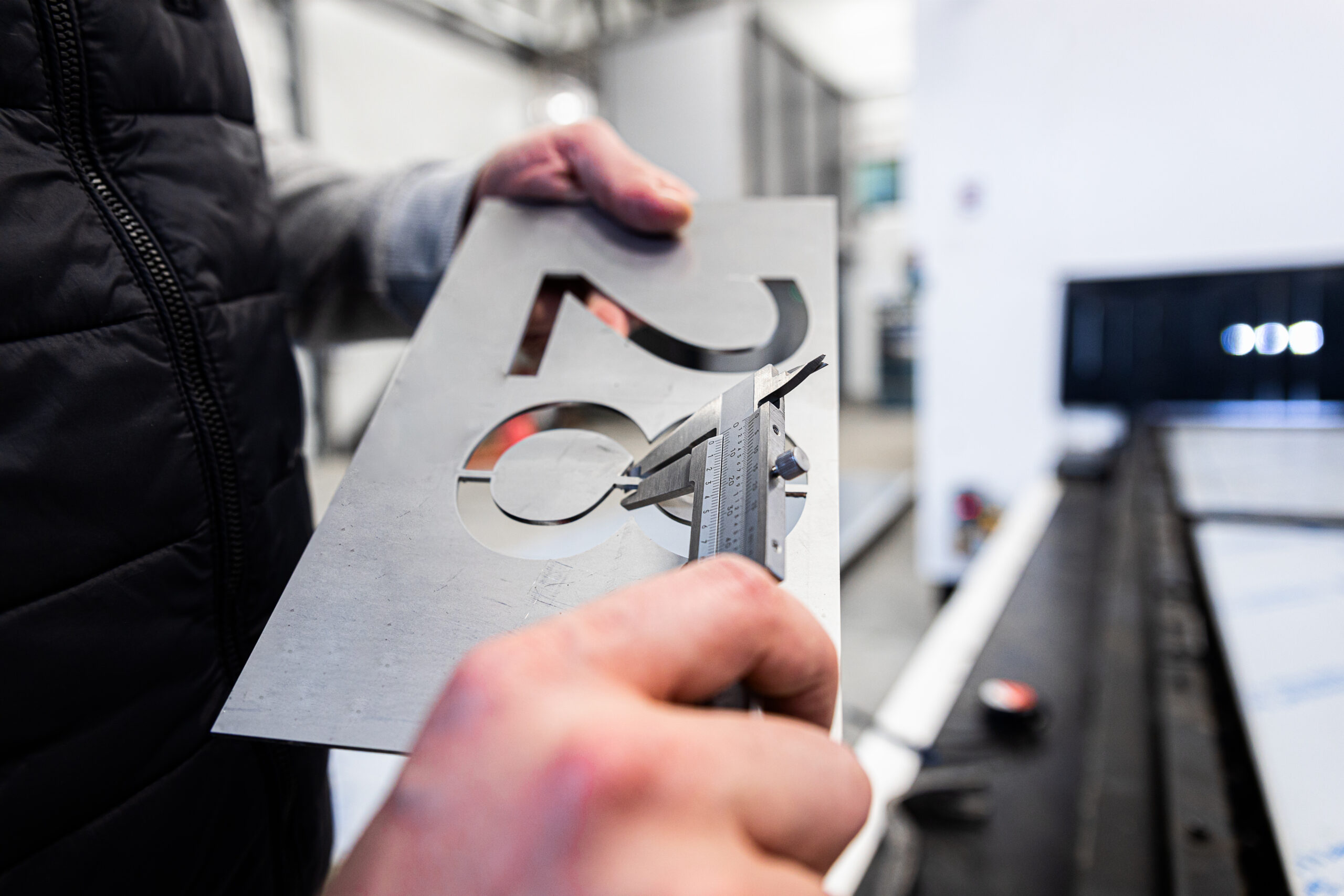 mans hands inspecting laser cut of metal plate