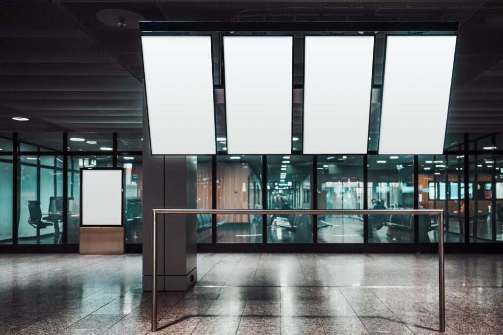 Suspended wayfinding signs hanging in a modern airport or transit terminal.